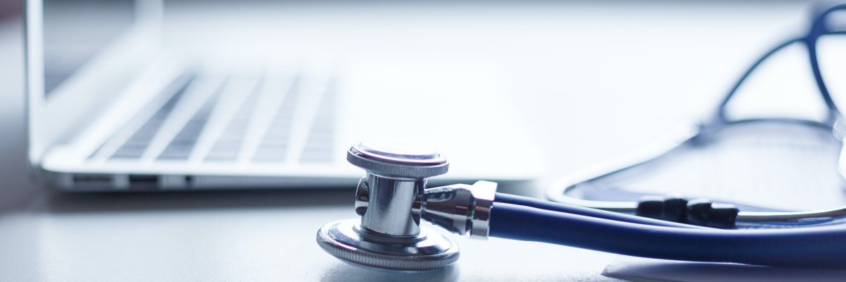 Stethoscope and laptop on doctor working desk