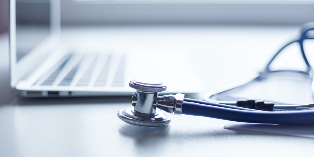 Stethoscope and laptop on doctor working desk